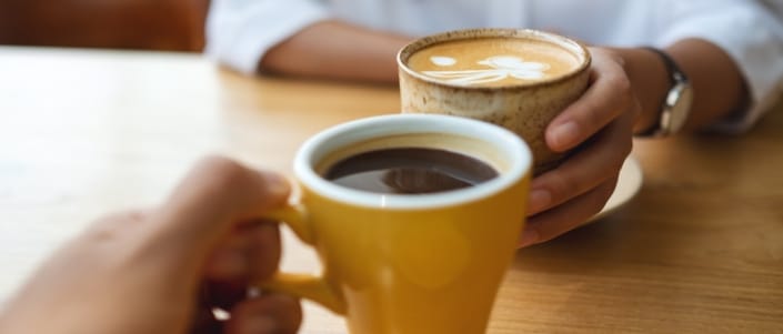 Two coffee cups about to touch